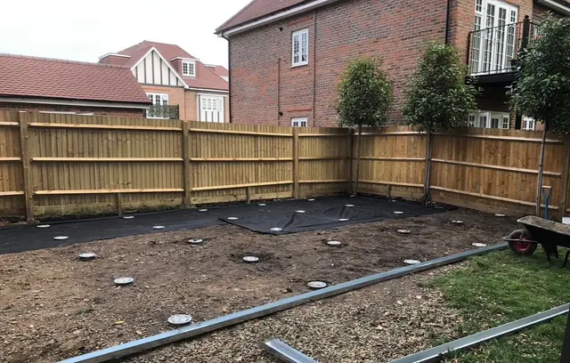 Large fenced garden footprint with installed screw heads, partial membrane and metal members in the foreground.